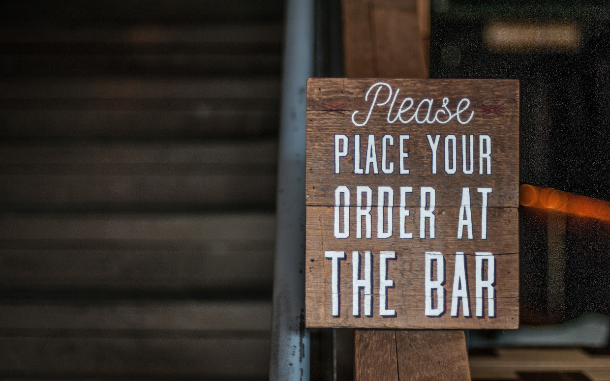 A painted sign that reads, 'Please place your order at the bar'.